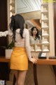 A woman standing in front of a mirror in a room.