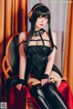 A woman in a black dress sitting on a chair.