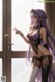 A woman with long purple hair standing in front of a window.