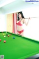 A woman in a red bikini standing next to a pool table.