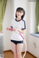 A woman in a white shirt and black shorts holding a pink hula hoop.