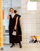 A woman in a black dress standing in front of a mirror.