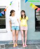 Two young women standing next to each other in front of a building.