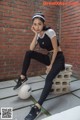 A woman sitting on a bench next to a soccer ball.