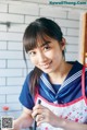 A woman in a sailor outfit holding a pen.