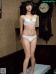 A woman in a white lingerie standing on a bed.