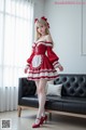 A woman in a red and white dress standing in front of a couch.