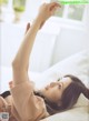 A woman laying on a bed with her arms outstretched.