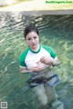 A woman in a green and white shirt is standing in the water.