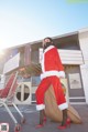 A woman in a santa suit is pushing a shopping cart.