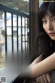 A woman leaning against a window looking out the window.