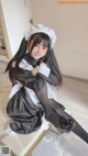 A woman in a maid outfit sitting on a table.