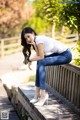 A woman sitting on a wooden bench in a park.