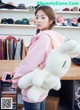 A woman in a pink hoodie holding a white stuffed animal.