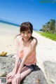 A woman sitting on a rock on the beach.