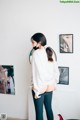 A woman standing in front of a mirror wearing a white sweatshirt and black pants.