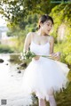 A woman in a white dress holding a bouquet of flowers.