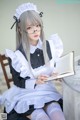 A woman in a maid outfit is reading a book.