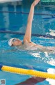 A woman swimming in a pool with her arms outstretched.