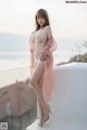 A woman in a pink lingerie posing on a balcony.