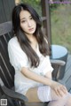 A woman sitting on a wooden chair wearing white stockings.