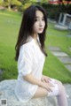 A woman in a white shirt and white stockings sitting on a rock.